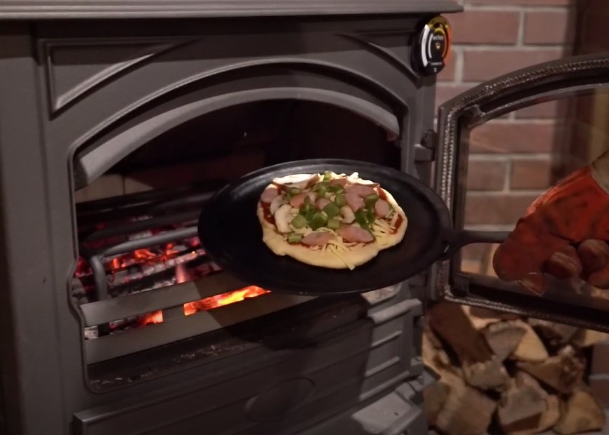 薪ストーブにピザパンに載せたピザを入れます